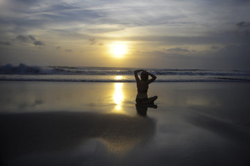 free woman sitting looking to sea sunset practicing yoga and meditation at beautiful Asian beach
