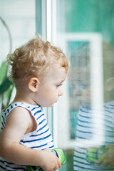 little boy watching the rain through the window