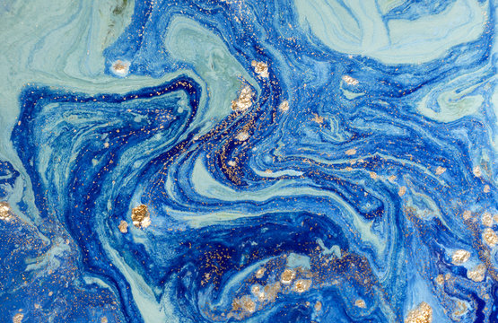 Marbled blue abstract background with golden sequins. Liquid marble ink pattern.