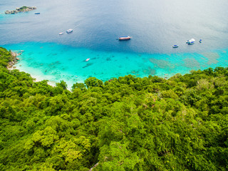 Fototapeta na wymiar Top aerial view of isolated beautiful tropical island with white sand beach, blue clear water and granite stones. Also top view of speedboats above coral reef. Similan Islands, Thailand.