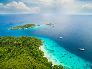 Obraz premium Top aerial view of isolated beautiful tropical island with white sand beach, blue clear water and granite stones. Also top view of speedboats above coral reef. Similan Islands, Thailand.