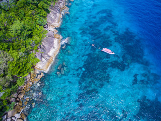 Aerial view of isolated tropical island with blue clear water and granite stones. Top view of coral...