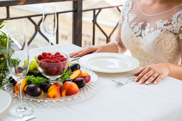Bride and groom sitting at a table on which there is a plate of fruit.