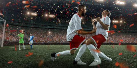 Soccer players emotionally happy after victory. Players joyfully screaming on the big professional...