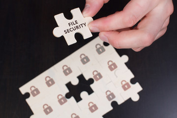 The concept of business, technology, the Internet and the network. A young businessman collects a puzzle with the proper inscription: File security