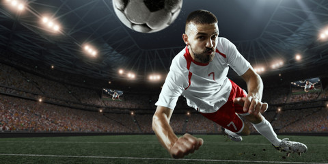 Soccer player performs an action play and beats the ball on a professional stadium. Player wears...