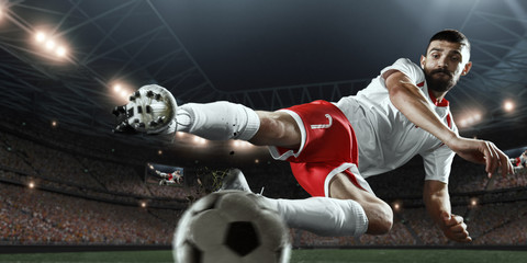 Soccer player performs an action play and beats the ball on a professional stadium. Player wears...