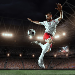 Soccer player performs an action play and beats the ball on a professional stadium. Player wears...