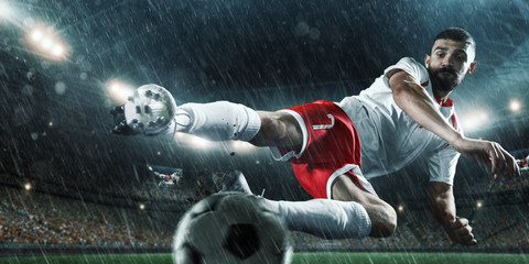 Soccer player performs an action play and beats the ball on a professional rainy stadium. Player...