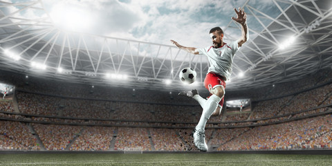Soccer player performs an action play and beats the ball on a professional stadium. Player wears...