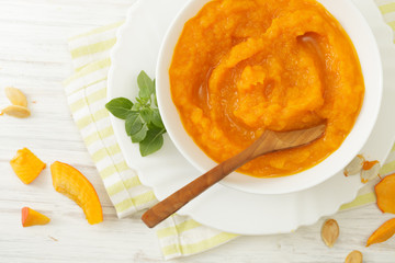 Pumpkin puree in a plate of pumpkin slices on a white table