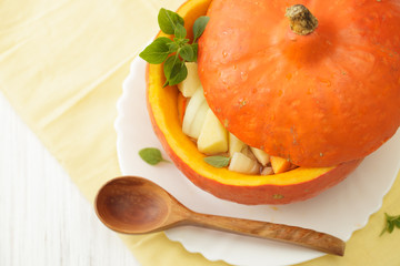 Closed pumpkin pot with a wooden spoon on a white table