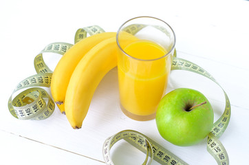 healthy eating, dieting, slimming and weigh loss concept - close up of green apple, banana, orange, juice, measuring tape.