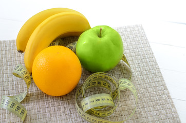 healthy eating, dieting, slimming and weigh loss concept - close up of green apple, banana, orange, juice, measuring tape.
