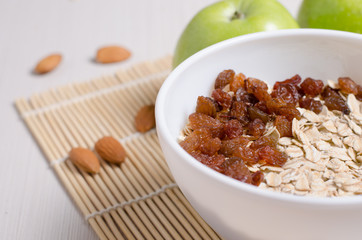 Oatmeal with raisins on the tablecloth from bamboo. Apples, almonds