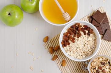 Oatmeal with raisins on the tablecloth from bamboo. Honey, chocolate, almonds, granola