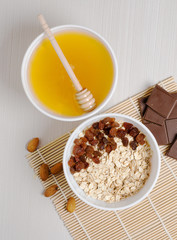Oatmeal with raisins on the tablecloth from bamboo. Honey, chocolate, almonds