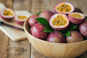 Passion fruit on wood bowl put on wood table in side view for background or wallpaper. Prepare passion fruit on cutting board for homemade dessert or cooking. Ripe passion fruit so sweet and sour.