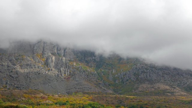 Fog in mountains in autumn morning  /Clouds over mountains covered with colorful forests 
