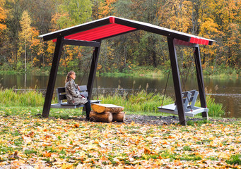 Lady sitting in the gazebo in the fall.
