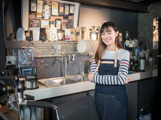 Asian women barista smiling standing at the coffee shop counter, female successful in small business owner.