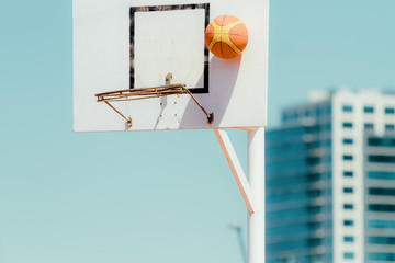 Basketball board with bouncing ball and office building in the background