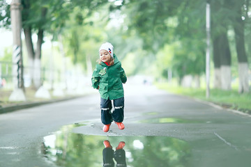 Fototapeta premium cold summer walk in the rain little girl puddles