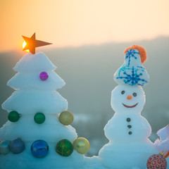 Snowman with smiley faces in hat on evening landscape