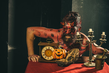 Halloween man with pumpkin, clock, candlestick on table