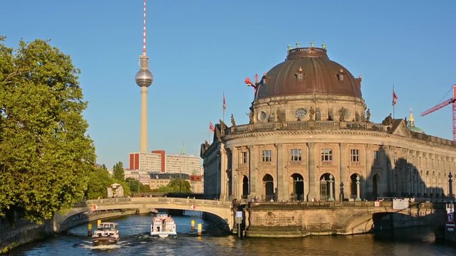 Boat cruises in front of the Bode Museum at sunset in Berlin.