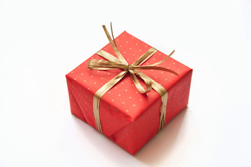 Red gift with golden bow on white background.