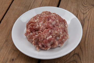raw ground meat on a white plate on a wooden table