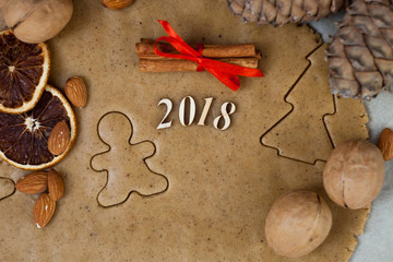 Fototapeta na wymiar Making gingerbread cookies. Dough, metal cutter, cinnamon, nuts, spices on background, number 2018