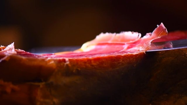 Jamon serrano. Slicing traditional spanish ham closeup. 4K UHD video 3840x2160 