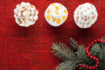 christmas decorated cupcakes at red burlap background top view