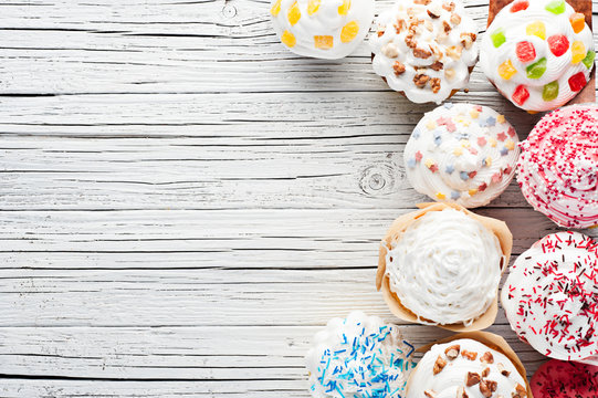 variety of cupcakes on white wooden background top view