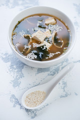 Bowl of asian miso soup, vertical shot on a white concrete background