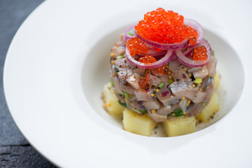 Close-up of herring tartar with potato and red caviar topping, selective focus