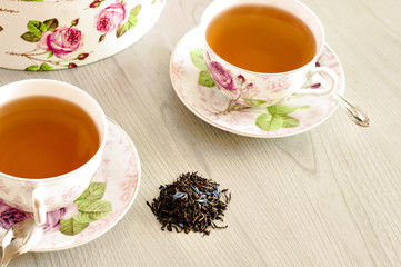 Red Hot Hibiscus tea in a glass mug on a wooden table among rose petals and dry tea custard with metallic heart