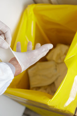 healthcare professional throwing away disposable latex gloves in trash