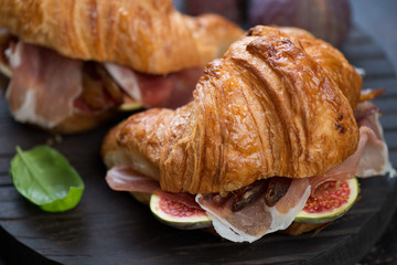 Close-up of croissants with prosciutto and slices of fig fruits, selective focus