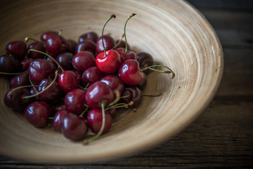 Cherry in a wooden plate in rustic style