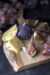 Ripe grapes and figs on dark wooden table