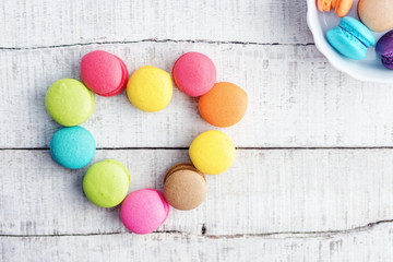 Fototapeta na wymiar Vibrant colorfull macarons in heart shape on white wooden table. Text space