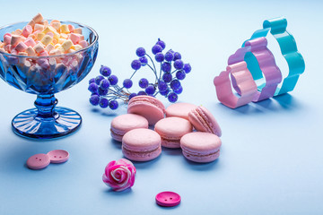 Pink Macaroons cakes with colorful fluffy marshmallows in blue vase.