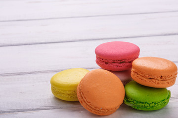 Group of colorful macaroons on white wooden background, with room for copy space