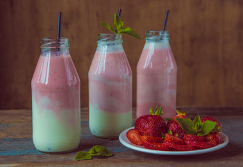 Smoothie with strawberry in bottles on wooden table