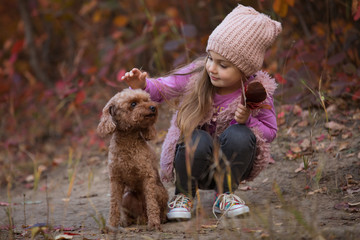 Little girl sitting with dog together on nature at the autumn day, art portrait