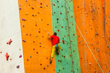 The active young man on rock wall in sport center