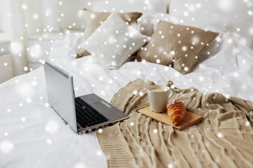 laptop, coffee and croissant on bed at cozy home